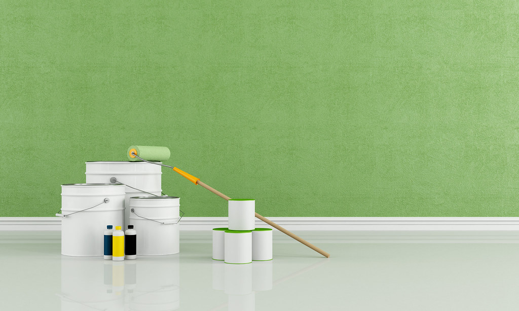 Paint roller and cans by a green wall